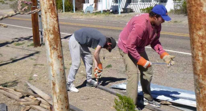 two students wearing gloves participate in a service project with outward bound